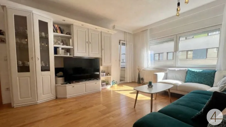 Helles Wohnzimmer mit Holzfußboden, großem Medienelement und bequemer Couch.