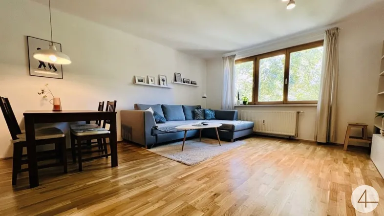 Heller Wohn- und Essbereich mit Parkettboden, bequemer Couch und Esstisch.