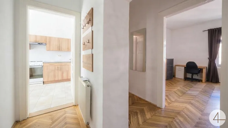 Heller Flur mit Fischgrätparkettboden, der zur Küche und einem weiteren Zimmer führt.