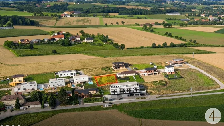Luftaufnahme eines Baugrundstücks in ländlicher Umgebung, umgeben von Feldern und modernen Wohnhäusern.
