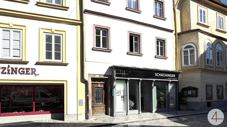 Eine belebte Straße mit mehreren Geschäftsfassaden und traditioneller Architektur unter blauem Himmel.