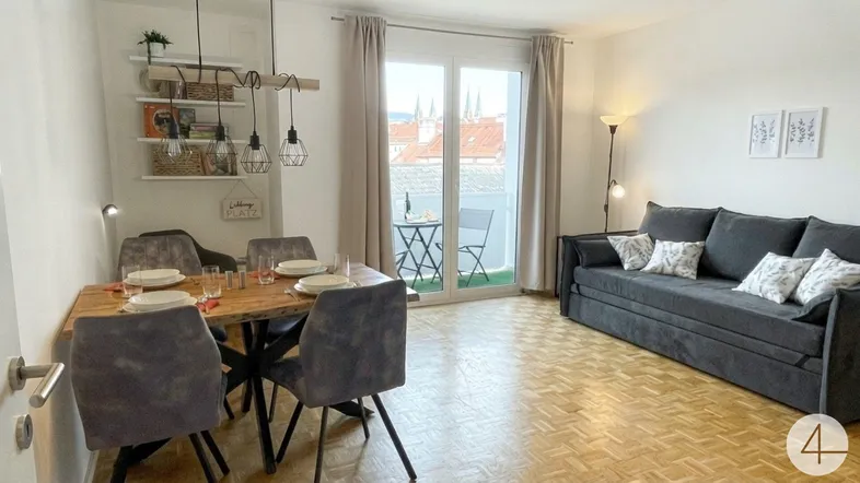 Heller Wohn- und Essbereich mit Holzboden, modernem Esstisch und Zugang zum Balkon mit Stadtblick.