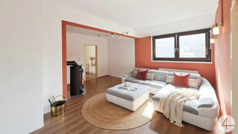 Helles Wohnzimmer mit modernem Sofa, Holzofen und Akzentwand in Terrakottafarbe.