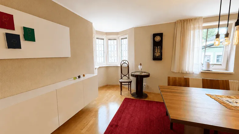 Heller Essbereich mit Holzboden, großem Esstisch und einem charmanten Erkerfenster.
