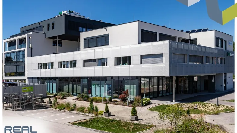 Modernes Geschäftsgebäude mit mehreren Etagen, großen Fenstern und integrierten Ladenflächen im Erdgeschoss.