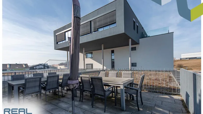 Geräumige Terrasse mit Esstisch und Sonnenschirm, ideal für Mahlzeiten im Freien mit Blick auf die Umgebung.