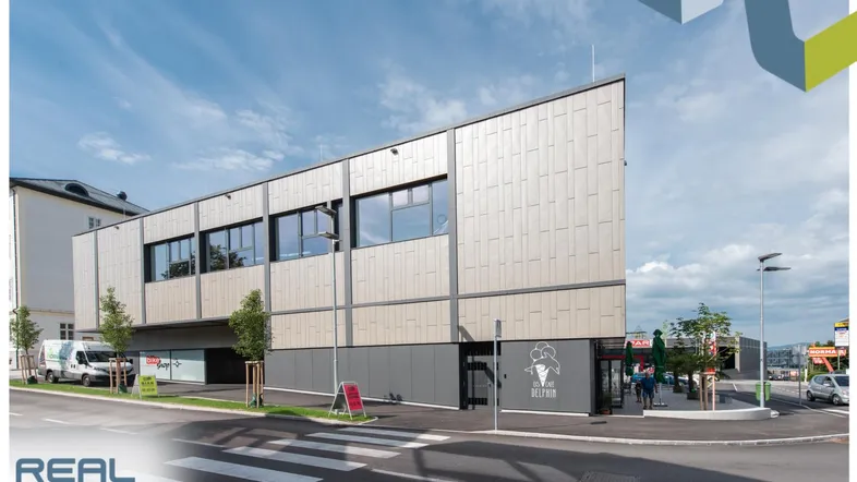 Modernes Geschäftsgebäude mit Holzverkleidung und großen Fenstern an einer Straßenecke.