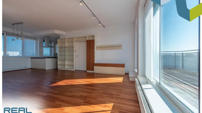 Helles, offenes Wohnzimmer mit Holzboden, großen Fenstern und Zugang zu einem Balkon.