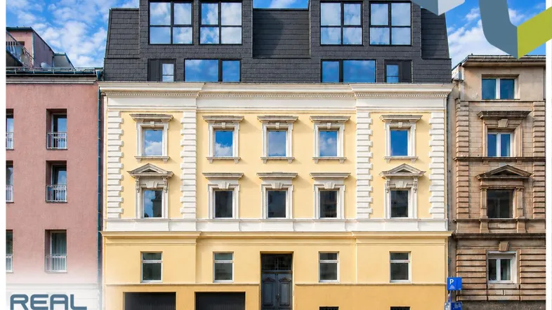 Historische Fassade mit moderner Dachaufstockung und großen Fenstern, gut gepflegt.
