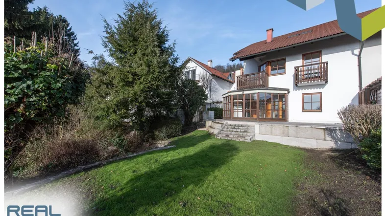 Großzügiger Gartenbereich mit Rasenfläche und Blick auf das Haus mit Wintergarten.