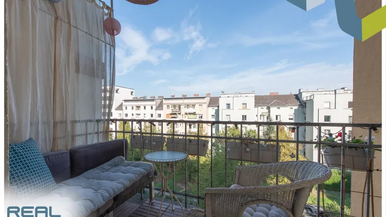 Gemütlicher Balkon mit Sitzgelegenheiten und Blick auf die umliegenden Gebäude und Grünflächen.