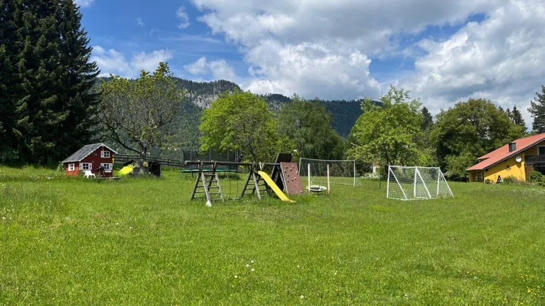 Großer Garten mit Spielplatz, Fußballtor und Blick auf die umliegende Berglandschaft.