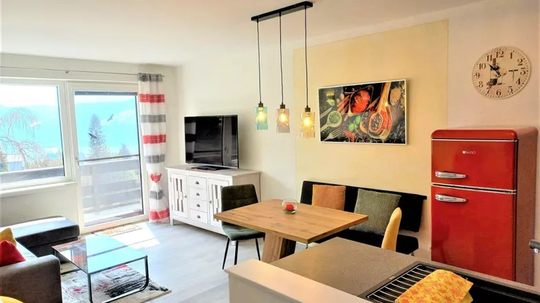 Helles Wohn- und Esszimmer mit Balkonzugang, moderner Einrichtung und Seeblick.