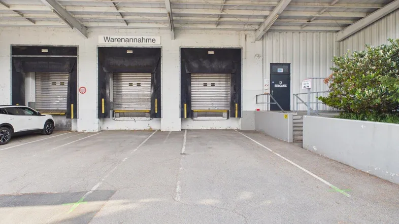 Außenansicht eines modernen Industriegebäudes mit mehreren Laderampen und einem geräumigen Parkplatz.