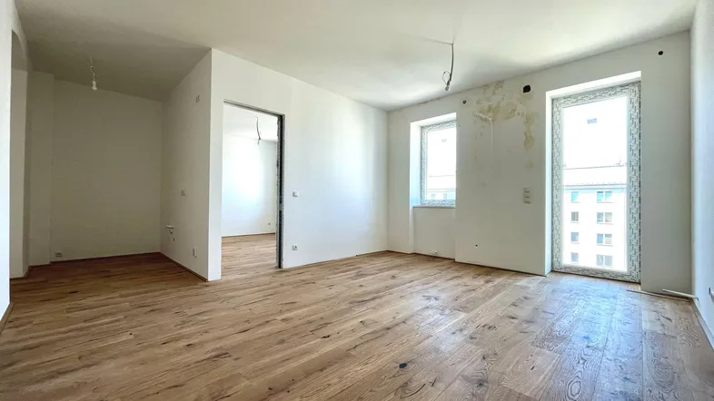 Helles, unmöbliertes Zimmer mit neuem Holzboden und weißen Wänden, bereit für die individuelle Gestaltung.