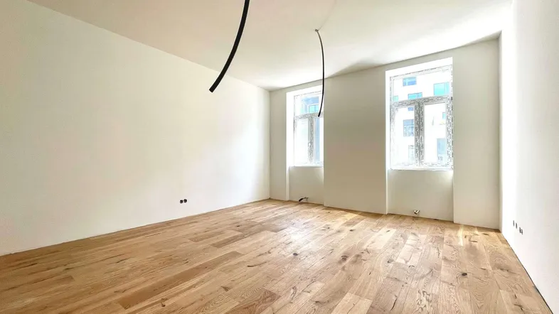 Heller Raum mit neu verlegtem Holzplankenboden und zwei Fenstern, bereit für die Einrichtung.