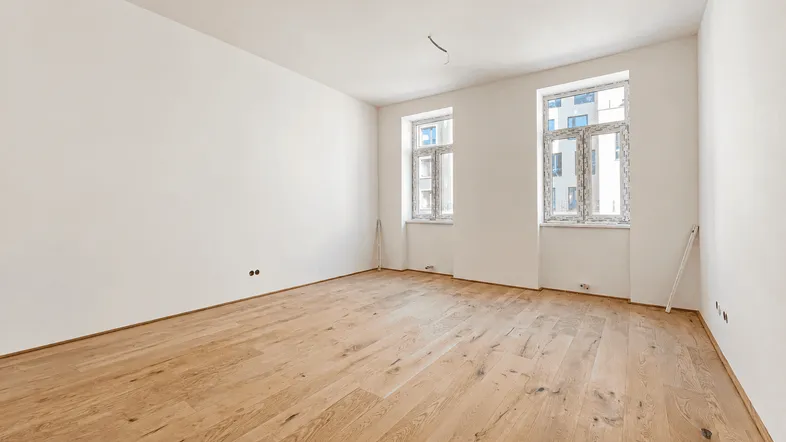 Helles, leeres Zimmer mit neuem Parkettboden und zwei Fenstern, bereit für die Einrichtung.