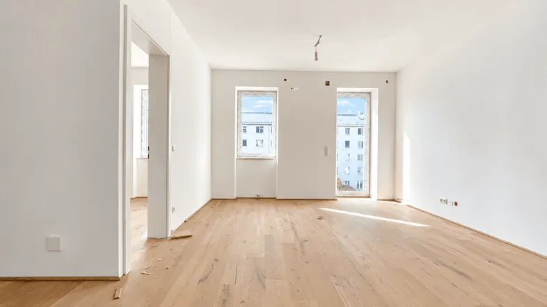 Helles, unmöbliertes Zimmer mit neuem Parkettboden und Blick auf die umliegenden Gebäude.