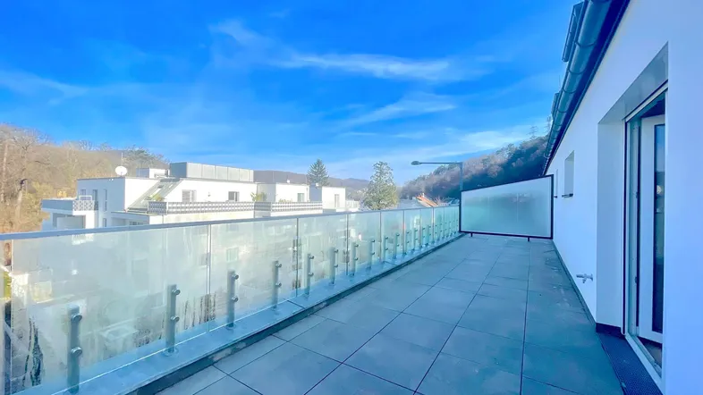 Geräumige Dachterrasse mit moderner Glasbrüstung und weitem Blick auf die Umgebung.