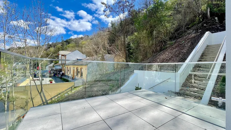 Geräumige Terrasse mit modernen Glasgeländern und Blick auf die umliegende Landschaft.