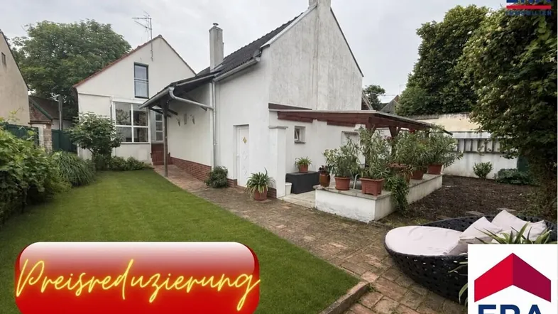 Weißes Einfamilienhaus mit gepflegtem Garten, Rasenfläche und überdachter Terrasse im Außenbereich.