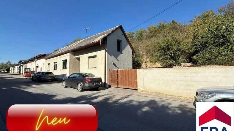 Außenansicht eines Gebäudes mit schlichter Fassade und einem geparkten Auto auf der Straße.