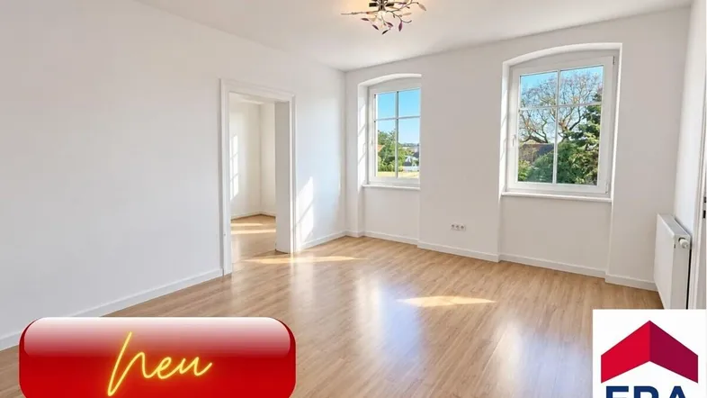 Helles, leeres Zimmer mit Laminatboden und zwei Fenstern, bereit zur individuellen Gestaltung.