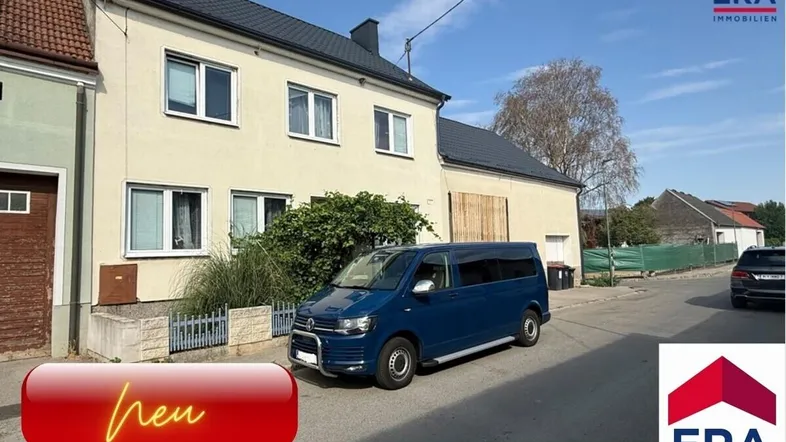 Ansicht des Mehrfamilienhauses von der Straße mit einem geparkten Fahrzeug davor.