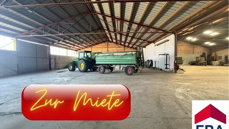 Geräumige Lagerhalle mit hoher Decke und Betonboden, ideal für landwirtschaftliche Fahrzeuge und Geräte.