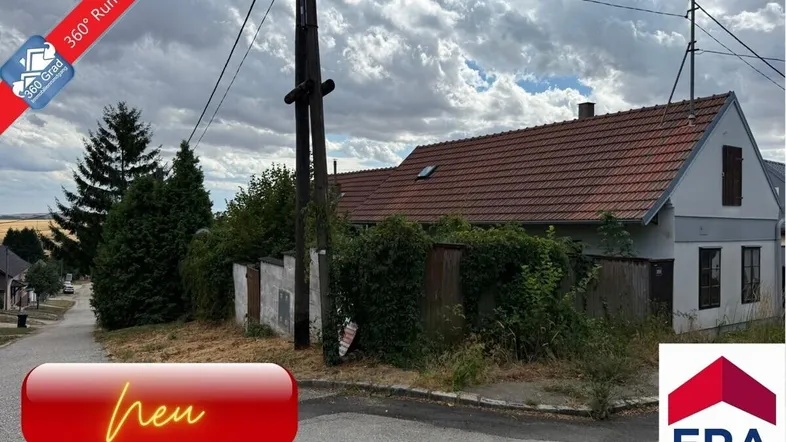 Ländliches Haus mit rotem Ziegeldach und verwildertem Gartenbereich an einer ruhigen Straße gelegen.
