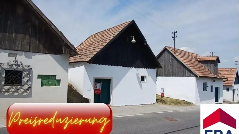 Mehrere traditionelle Kellerhäuser entlang einer ländlichen Straße mit Preisreduzierungshinweis.