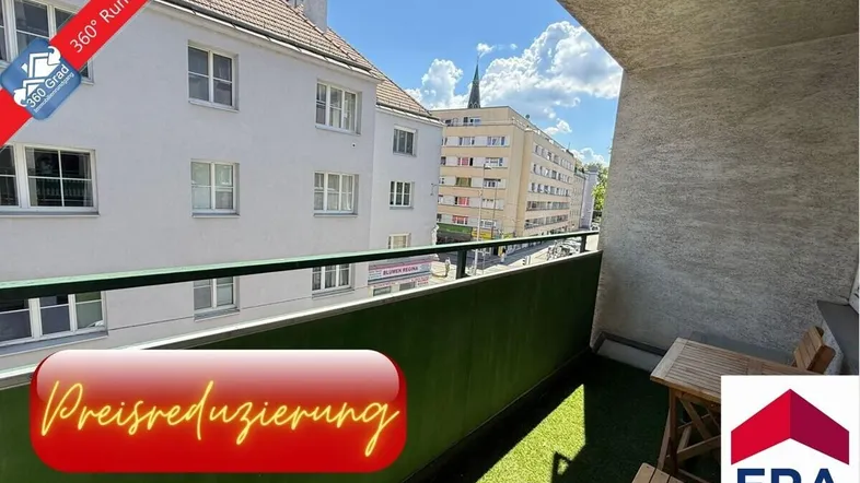Heller Balkon mit Kunstrasen, kleinem Holztisch und Blick auf die umliegenden Gebäude und die Stadt.