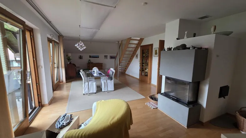Geräumiger Wohn- und Essbereich mit Kamin, Holzboden und Zugang zu einem Balkon.