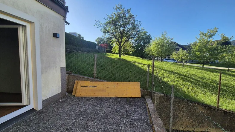 Gepflasterte Terrasse mit Zugang zum Haus und Blick auf die grüne Umgebung.