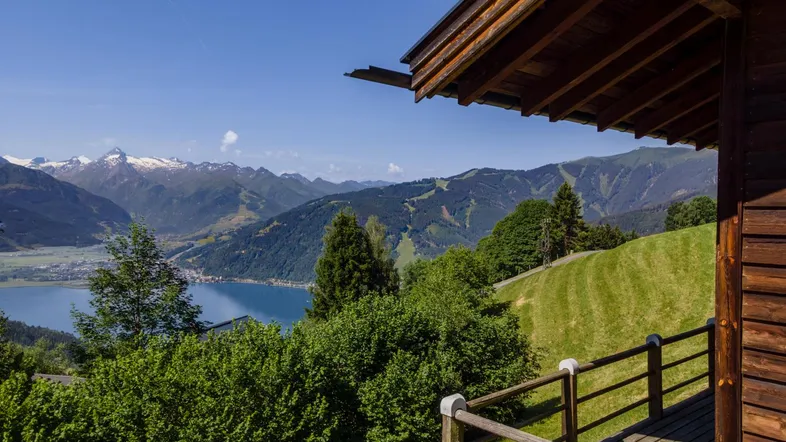 Blick von einem Holz-Balkon auf einen malerischen See und die umliegende Berglandschaft.