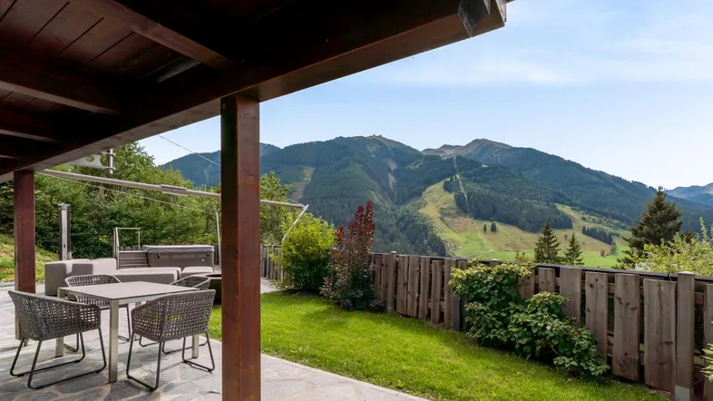 Gemütliche überdachte Terrasse mit Sitzgelegenheiten, Whirlpool und atemberaubendem Bergblick.