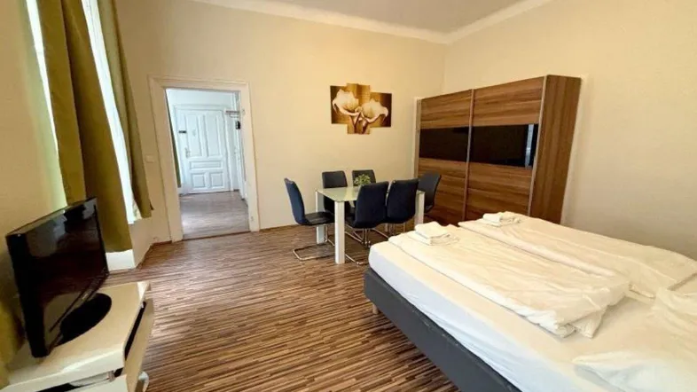 Helles Zimmer mit Schlafbereich, Esstisch und TV-Möbel, ideal für ein Studio-Apartment.