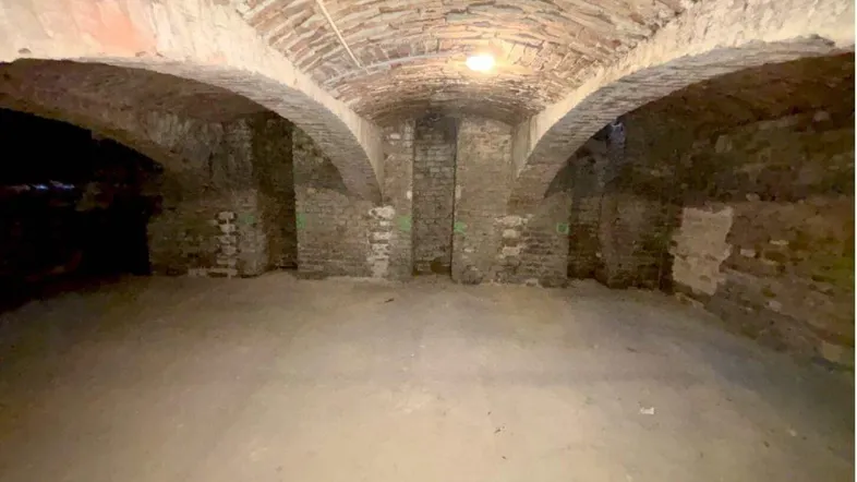 Historischer Kellerraum mit beeindruckendem Ziegelgewölbe und robustem Betonboden, der eine einzigartige Atmosphäre schafft.