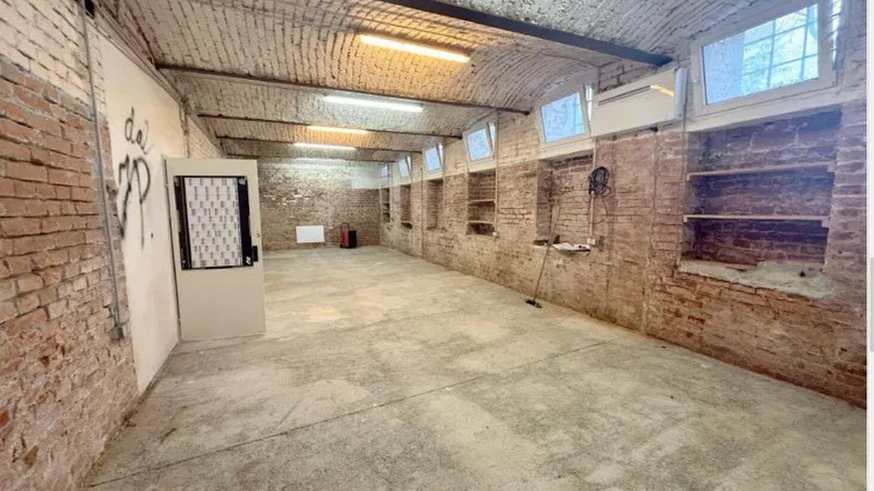 Großer, leerer Raum mit unverputzten Ziegelwänden und gewölbter Decke, ideal für Lagerzwecke und Renovierung.