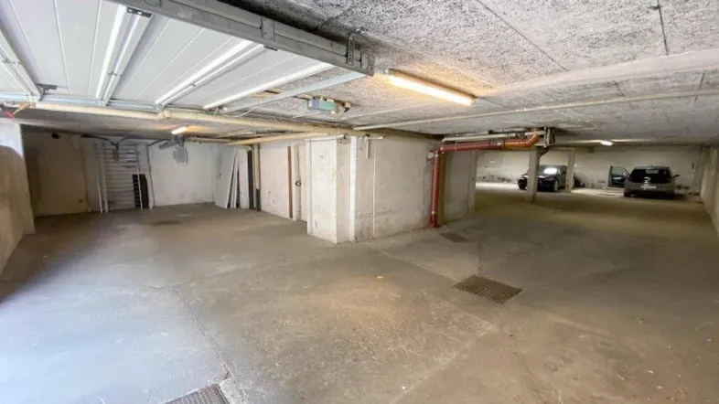 Geräumige Tiefgarage mit Betonboden und Deckenbeleuchtung, bietet ausreichend Platz für Fahrzeuge.