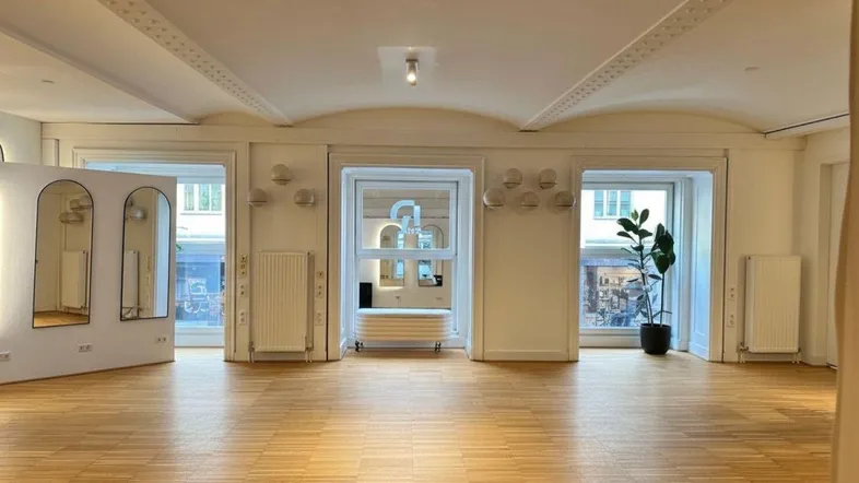 Heller, offener Raum mit Parkettboden, großen Fenstern und dekorativer Decke, ideal für gewerbliche Nutzung.