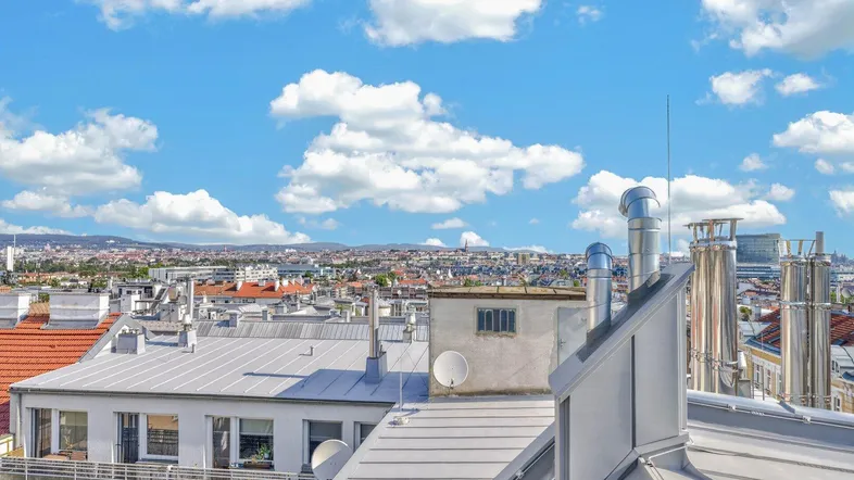 Panoramablick über die Dächer der Stadt mit blauem Himmel und vielen Wolken.