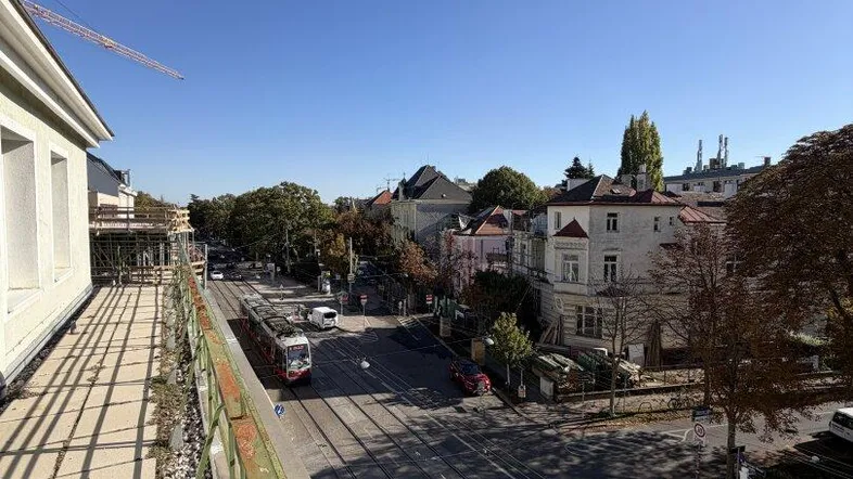 Langer Balkon mit Blick auf die Straße und die umliegenden Gebäude unter blauem Himmel.