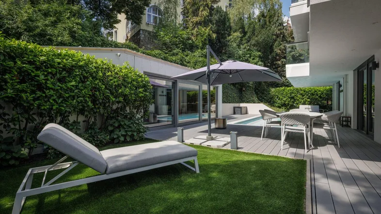 Großzügiger Außenbereich mit Kunstrasen, Holzterrasse, Pool und gemütlicher Lounge-Ecke.