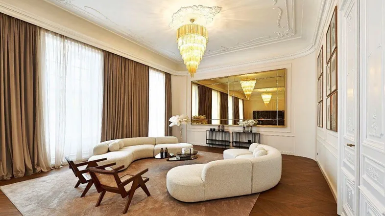 Großzügiges Wohnzimmer mit geschwungenen Sofas, Parkettboden und opulentem Kronleuchter.