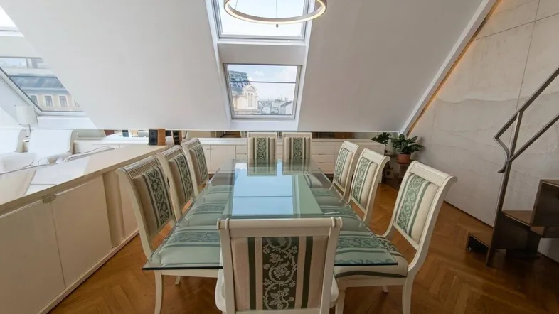 Helles Esszimmer im Dachgeschoss mit Holzboden, großen Dachfenstern und Blick auf die Stadt.