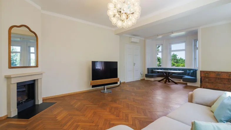 Helles Wohnzimmer mit Fischgrätparkett, modernem Kamin und gemütlicher Sitzecke am Erkerfenster.
