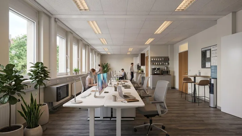 Modernes Großraumbüro mit mehreren Arbeitsplätzen, natürlichem Licht und einer kleinen Teeküche im Hintergrund.