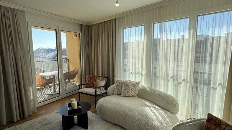 Helles Wohnzimmer mit modernem Sofa, Holzboden und direktem Zugang zum sonnigen Balkon.