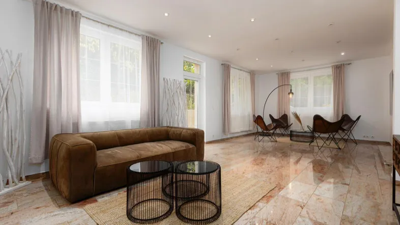 Geräumiges Wohnzimmer mit modernem Sofa, Couchtischen und hellem Marmorboden.